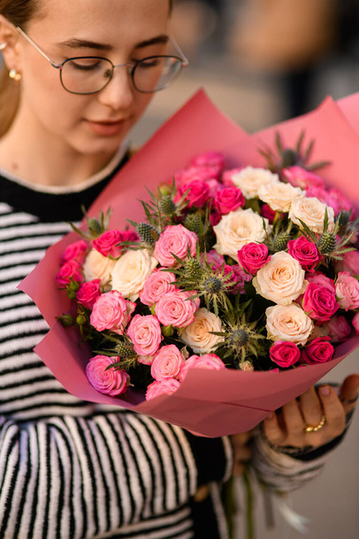 Vista ravvicinata su fiori freschi di mazzo con rose bianche e rosa e cardo nelle mani della donna - Foto, immagini