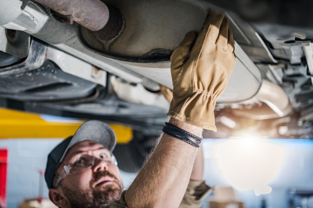 Closeup of Car Catalytic Converter Being Checked by Professional Mechanic at Vehicle Repair Station. Spodní pohled. Motiv automobilového průmyslu. - Fotografie, Obrázek