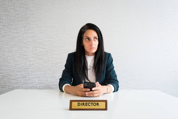 Молода біла брюнетка бізнес-леді директор в офісі вдумливий підприємець тримає телефон приймати рішення думати, перш ніж текст р сміється ізольовано
 - Фото, зображення