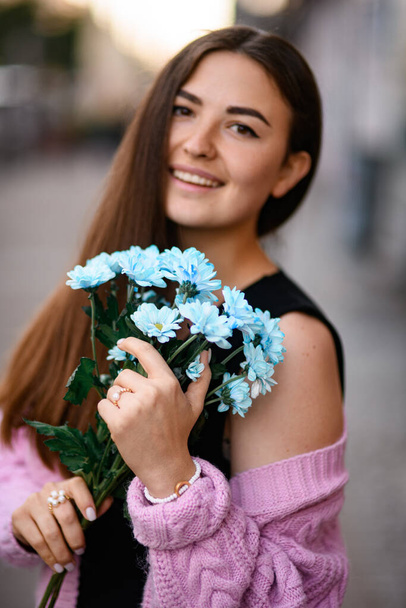 bunch of blue chrysanthemum flowers in the hands of young beautiful smiling woman. Female portrait - Photo, image