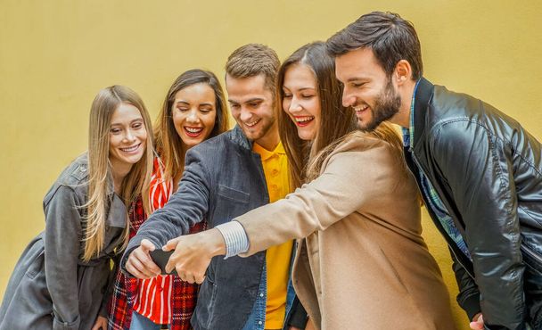 Älypuhelimia käyttävät nuoret - Sosiaalisen median työtovereiden ryhmä pitää hauskaa ja ottaa selfie - Pakkomielle verkko- ja jakamishetkiin - Teknologian käsite - Valokuva, kuva