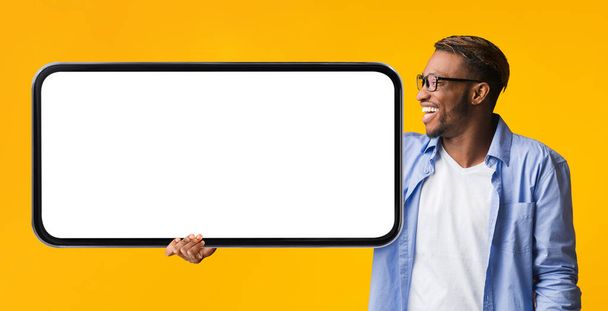 Mobil Mockup. Happy black man looking at big blank smartphone in hand, vidám afro-amerikai férfi ajánlja online ajánlat, reklám új honlap vagy alkalmazás, panoráma, mockup - Fotó, kép