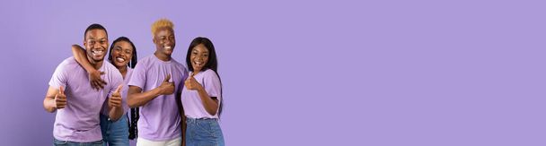 Alegres jóvenes afroamericanos haciendo gestos sobre fondo de estudio púrpura, dos parejas negras enamoradas abrazando y mostrando pulgares, recomendando algo, panorama con espacio para copiar anuncios, collage - Foto, imagen