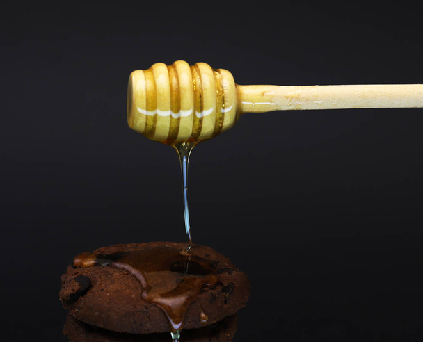 Flowing honey on cookies in dark light. Shallow depth of field - Photo, image