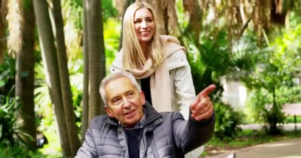 Nature, senior man in wheelchair with woman on garden path, quality time with daughter on outdoor walk. Retirement disability and senior care, grandpa and happy woman caregiver in park with trees. - Filmagem, Vídeo