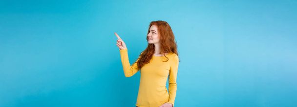 Close up Portrait young beautiful attractive redhair girl happy with something and pointing finger. Blue Pastel Background. Copy space. - Foto, Imagen