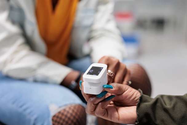 パルス酸素濃度計を保持する薬剤師は、測定結果を閉じます。患者の酸素飽和度測定、ドラッグストアでの顧客のハートビート測定、医療機器の近接ビュー - 写真・画像