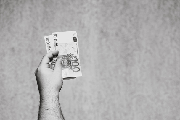 Ручна рука тримає і показує євро гроші або дає гроші. Всесвітня фінансова концепція, 100 євро банкноти EURO ізольовані. Концепція багатих бізнесменів, заощадження або витрачання грошей.. - Фото, зображення