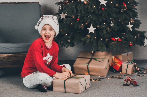 Hediye. Kırmızı pakette Noel ağacının altında bir hediye. Yılbaşı. Çocuklar hediyeleri açar. - Fotoğraf, Görsel