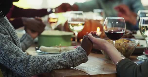 Las manos, la oración y la familia en una mesa para comer, dar gracias y adorar antes de almorzar juntos en una casa. Rezad, tomados de la mano y los amigos se unen en oración para bendecir la cena, la Navidad y la reunión. - Metraje, vídeo