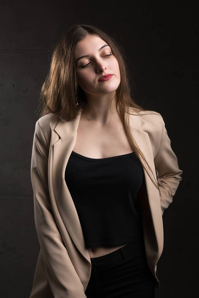 Portrait of a young brunette with long hair in the studio. Dramatic photo in dark colors. - Foto, afbeelding