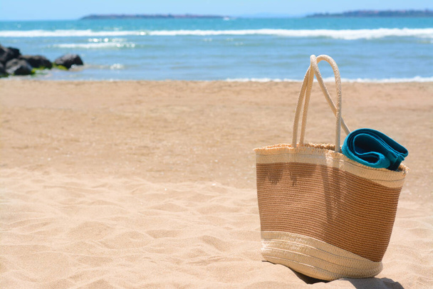 Soft blue towel in beach bag on sand near sea, space for text - Fotoğraf, Görsel