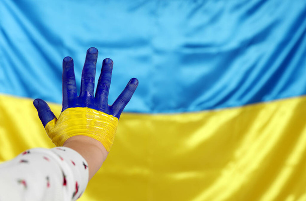 Little girl with paint on hand near Ukrainian flag, closeup. Space for text - Фото, изображение
