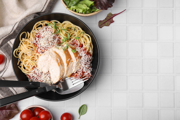 Delicious pasta with tomato sauce, chicken and parmesan cheese on white tiled table, flat lay. Space for text - Zdjęcie, obraz