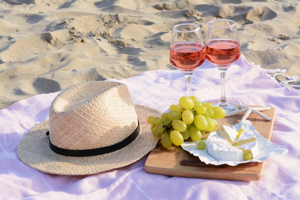 Glasses with rose wine and snacks for beach picnic on sand outdoors - Fotoğraf, Görsel