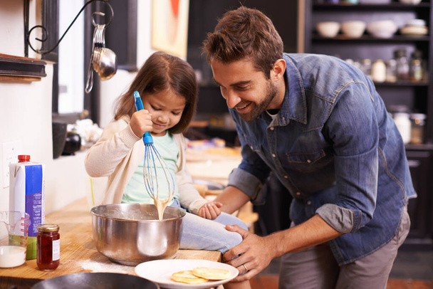 Pärjäät hienosti, kultaseni. Söpö pieni tyttö auttaa isäänsä tekemään pannukakkuja kotona - Valokuva, kuva