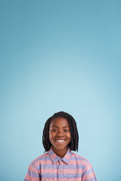 Nuoruuden itseluottamusta. Muotokuva onnellisesta nuoresta pojasta seisomassa sinistä taustaa vasten - Valokuva, kuva