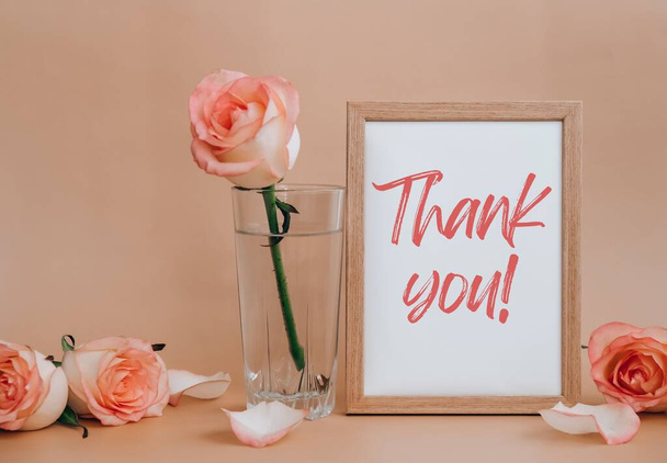 Mockup Wooden frame with text THANK YOU on blank and delicate pink roses on beige background. Minimal trendy composition. Romantic pastel pink rose flowers. Neutral earth tones. Greeting card holiday - Fotoğraf, Görsel
