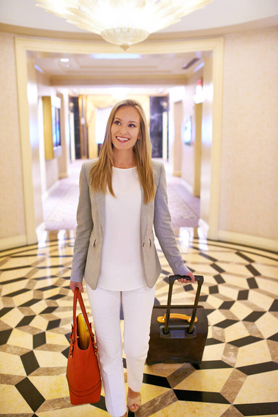 Ive arrived. a woman walking down the corridor of a hotel with a suitcase - Foto, Imagen