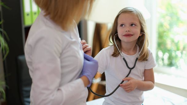 Portrait of smiling little child using medical stethoscope at doctor appointment. Healthcare, medicine and childhood concept - 写真・画像