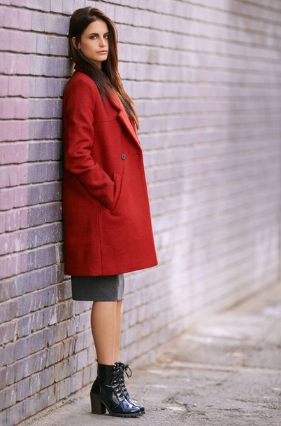 Signora in rosso. Ritratto di una splendida giovane donna appoggiata a un muro di mattoni in città - Foto, immagini