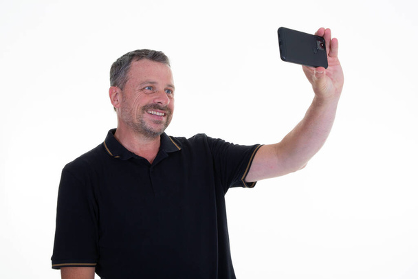 Man knap uitziende scherm camera mobiele telefoon smartphone maken selfie geïsoleerd op witte achtergrond - Foto, afbeelding