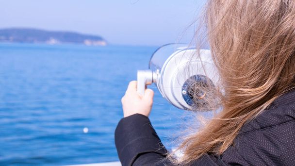 Tourist looking through coin operated binoculars. Binocular telescope on the observation deck for tourism. Sea background. Binoculars watching at horizon at ship deck. Discover new places Travel - Fotoğraf, Görsel