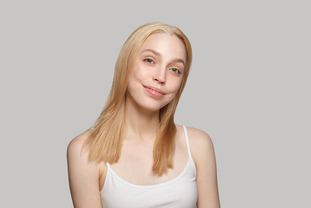 Красивая блондинка с длинными светлыми волосами и свежей кожей на белом фоне - Фото, изображение