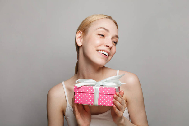 Portrait d'une jolie jeune femme blonde avec coffret cadeau rose - Photo, image
