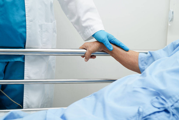 Лікар тримає за руки азіатську стареньку жінку пацієнтку, допомогу та догляд у лікарні.. - Фото, зображення