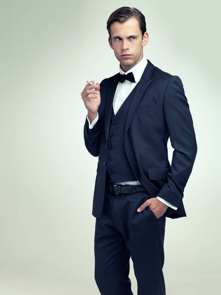 Dapper is a state of mind. A studio portrait of a confident young gentleman smoking a cigarette - Photo, Image