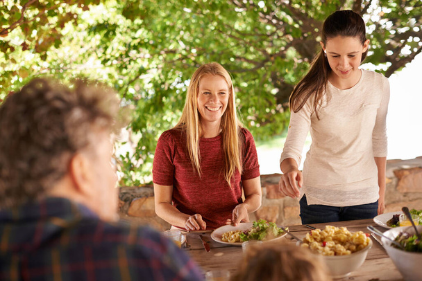 Family mealtimes are the best. A view of a family preparing to eat lunch together outdoors - Photo, Image