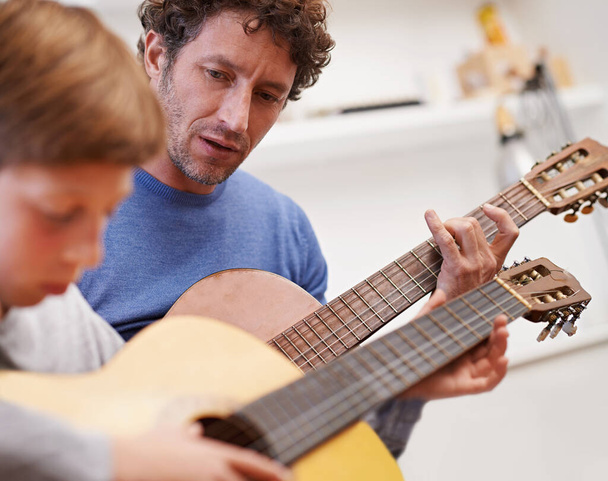 Hij heeft muziek in zich. een vader die zijn zoon de gitaar leert - Foto, afbeelding