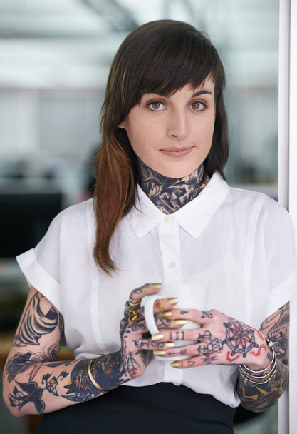 Stereotypes - who needs em. A cropped shot of a tattooed businesswoman standing in her office with a cup of coffee - Photo, Image