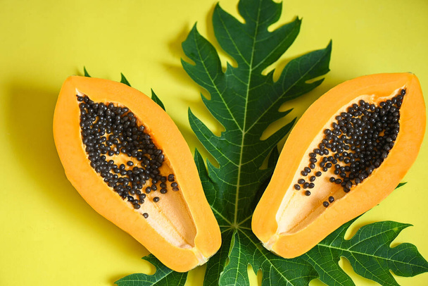fruits de papaye sur fond jaune, tranche de papaye fraîche et mûre fruits tropicaux avec graines de papaye et feuilles de papaye - vue de dessus - Photo, image