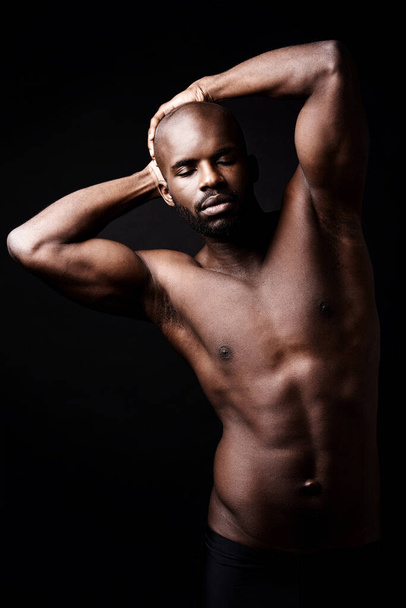 Hes all masculinity and muscles. Studio shot of a muscular man stretching with his hands on his head - Foto, immagini