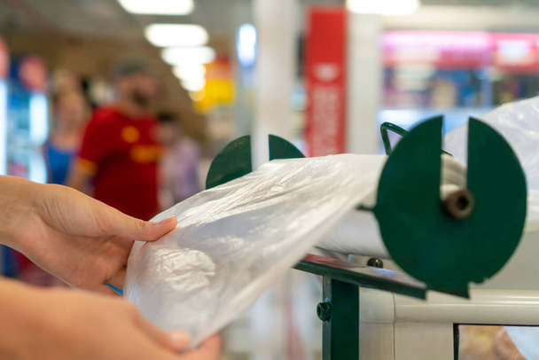 Primer plano de las manos de las mujeres arrancando una bolsa de celofán biodegradable para empacar en una tienda de comestibles - Foto, imagen