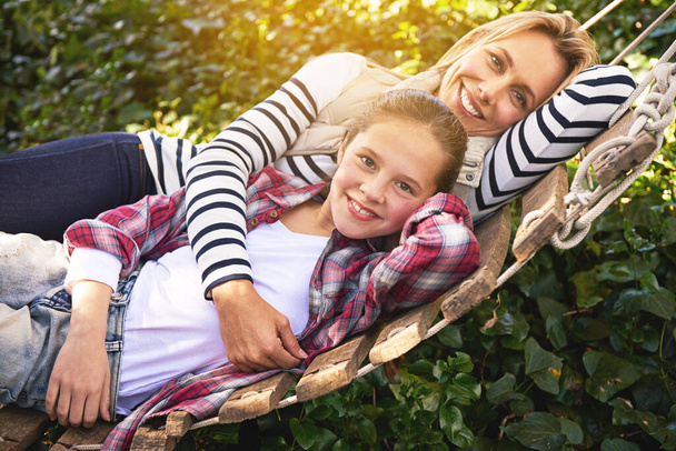Nuestro tiempo juntos no tiene precio. Una madre y una hija tumbadas en una hamaca juntas en el jardín - Foto, imagen