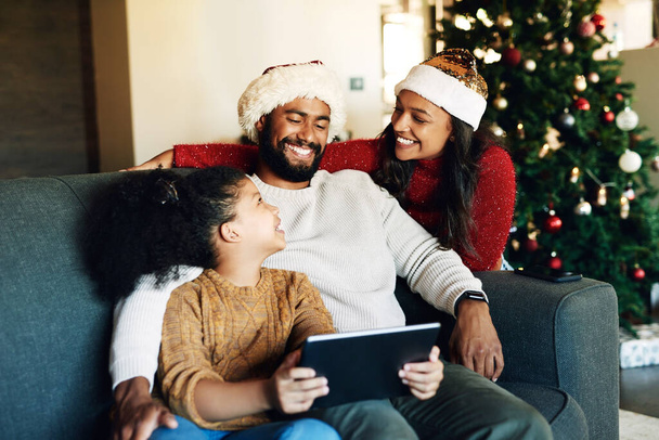 Christmas, family and tablet on sofa in home streaming movie or internet browsing. Xmas, love and girl, father and mother with digital touchscreen bonding, caring and enjoying holiday time together - Foto, immagini