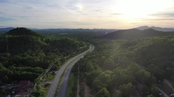 Aerial landscape of 4 lane road with residential area, forest, mountain,  blue sky and sunlight with high angle view of main road from Drone shot in Tak province, northern countryside of Thailand. - Footage, Video