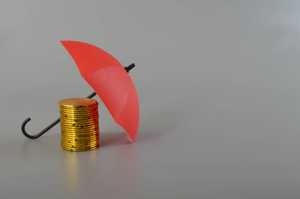 Red umbrella and the stack of coins. Keeping money safe. savings protection, Investment and capital insurance concept. - Photo, Image