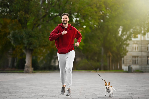 Man running with adorable Jack Russell Terrier on city street. Dog walking - Valokuva, kuva