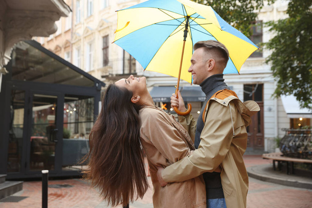 Lovely young couple with umbrella together under rain on city street - Foto, Bild