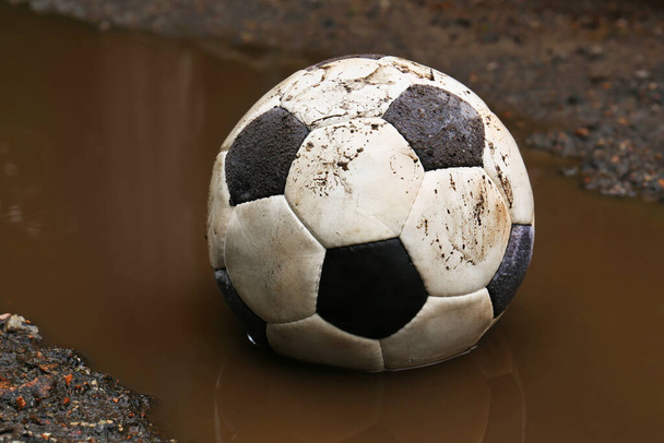 Dirty soccer ball in muddy puddle, closeup - Valokuva, kuva