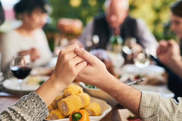 Party, food and family holding hands for prayer before eating chicken, barbecue or turkey at a social event. Corn, Christmas and Christian friends praying before enjoying meat and vegetables meal. - Фото, зображення