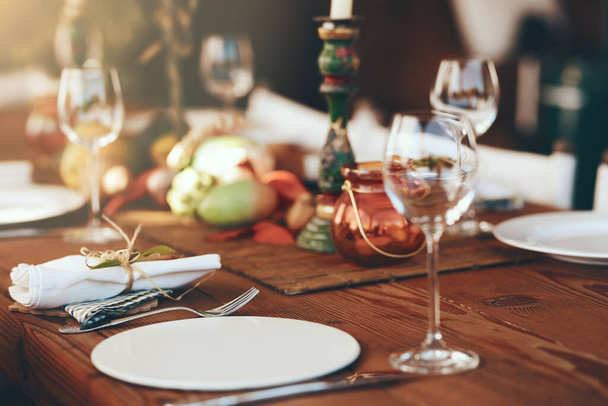 Table, wine glass and plate for festive holiday meal, drinking and celebration with blurred background. Fine dining, party and glass for wine at feast, dinner or lunch in home, house or restaurant. - 写真・画像