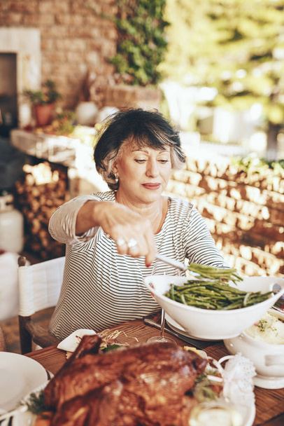 Vacsora, étel és idős nő étellel egy szabadtéri vacsora, party vagy esemény a kertben. Étkezés, ebéd és idős hölgy felszolgáló zöldségek sült hús egy külső étkező asztal otthonában - Fotó, kép