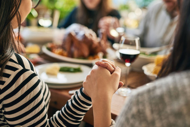 Food, praying and family holding hands for prayer with parents and children gathering at a dinner table at home. God, worship and grateful people with gratitude enjoy a thanksgiving meal with turkey. - Photo, Image