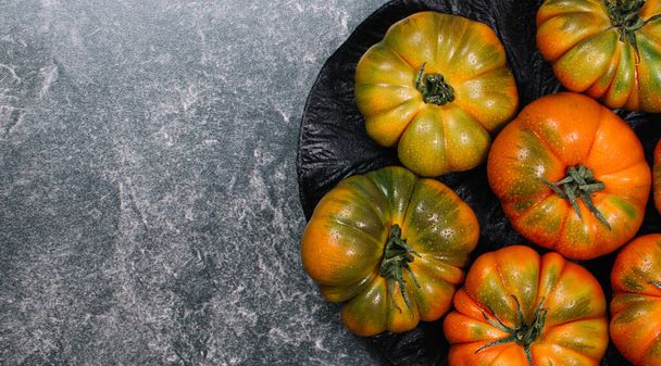 A group of Costoluto big tomatoes on a grey background, space for text, rustic concept - Foto, imagen
