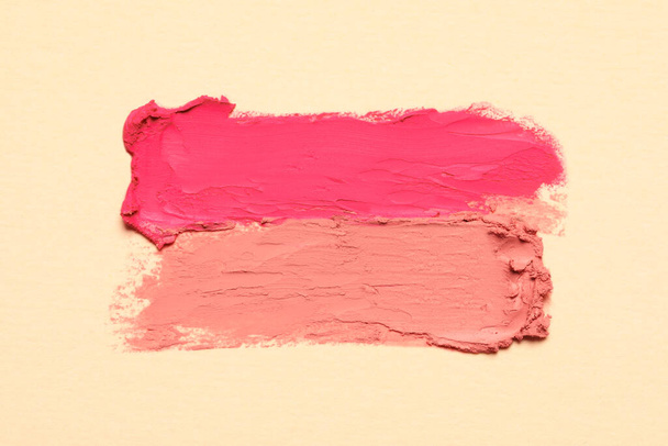 Smears of beautiful lipsticks on beige background, top view - Photo, image